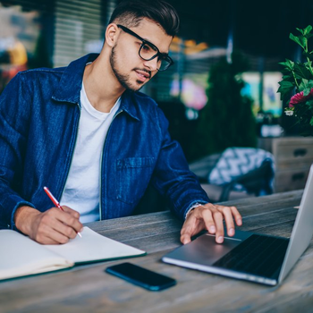 Young man taking notes form his computer at a coffee shop