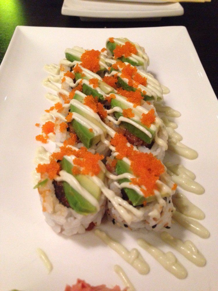 Sushi roll topped with salmon, avocado and spicy mayo drizzle