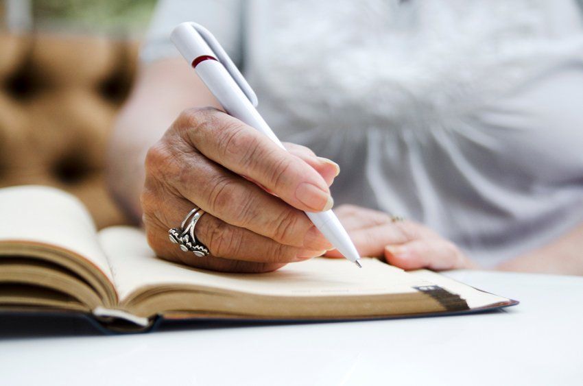 Senior Woman Writing With Pencil On Open Note Book — Johnson City, TN — Pectol & Miles Senior Woman Writing With Pencil On Open Note Book — Johnson City, TN — Pectol & Miles