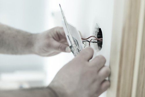 Electrician Installing Plug Outlet — Electrical Services in Wilmington, IL Electrician Installing Plug Outlet — Electrical Services in Wilmington, IL