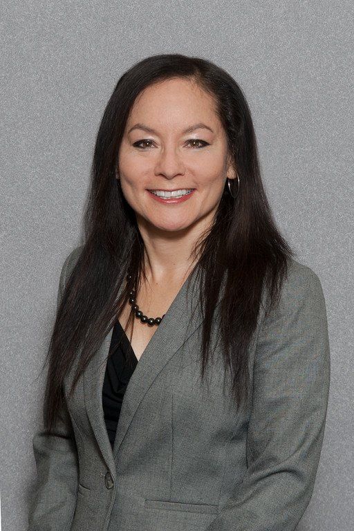 Portrait of a smiling woman in a gray blazer against a gray background