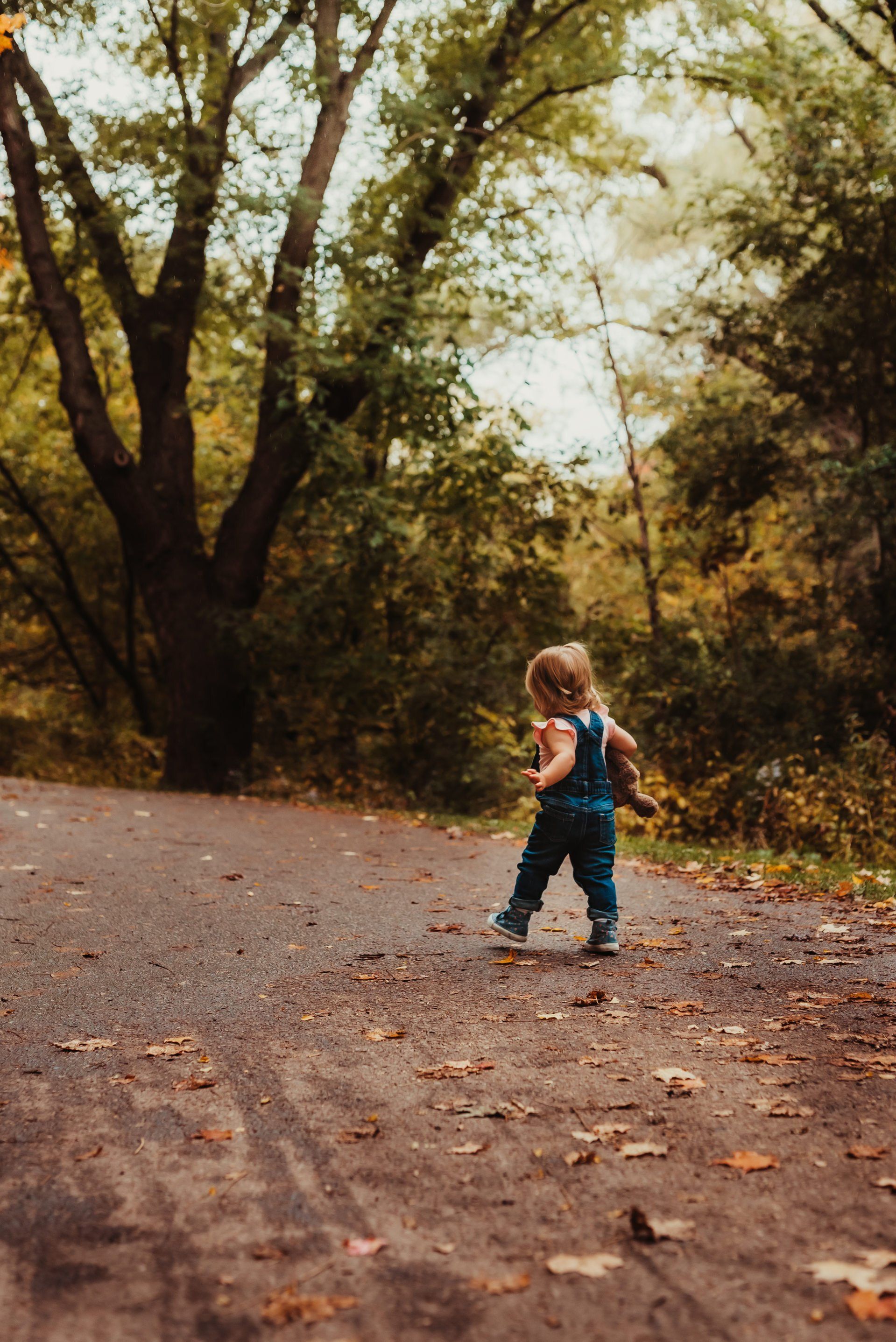 Toddler walking away on dirt covered road