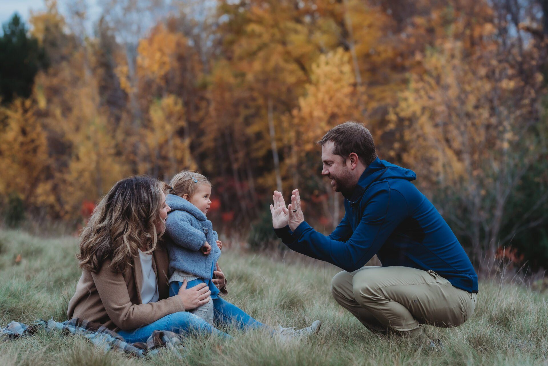 Photo of parents with toddler playing in a grassy field for family photography