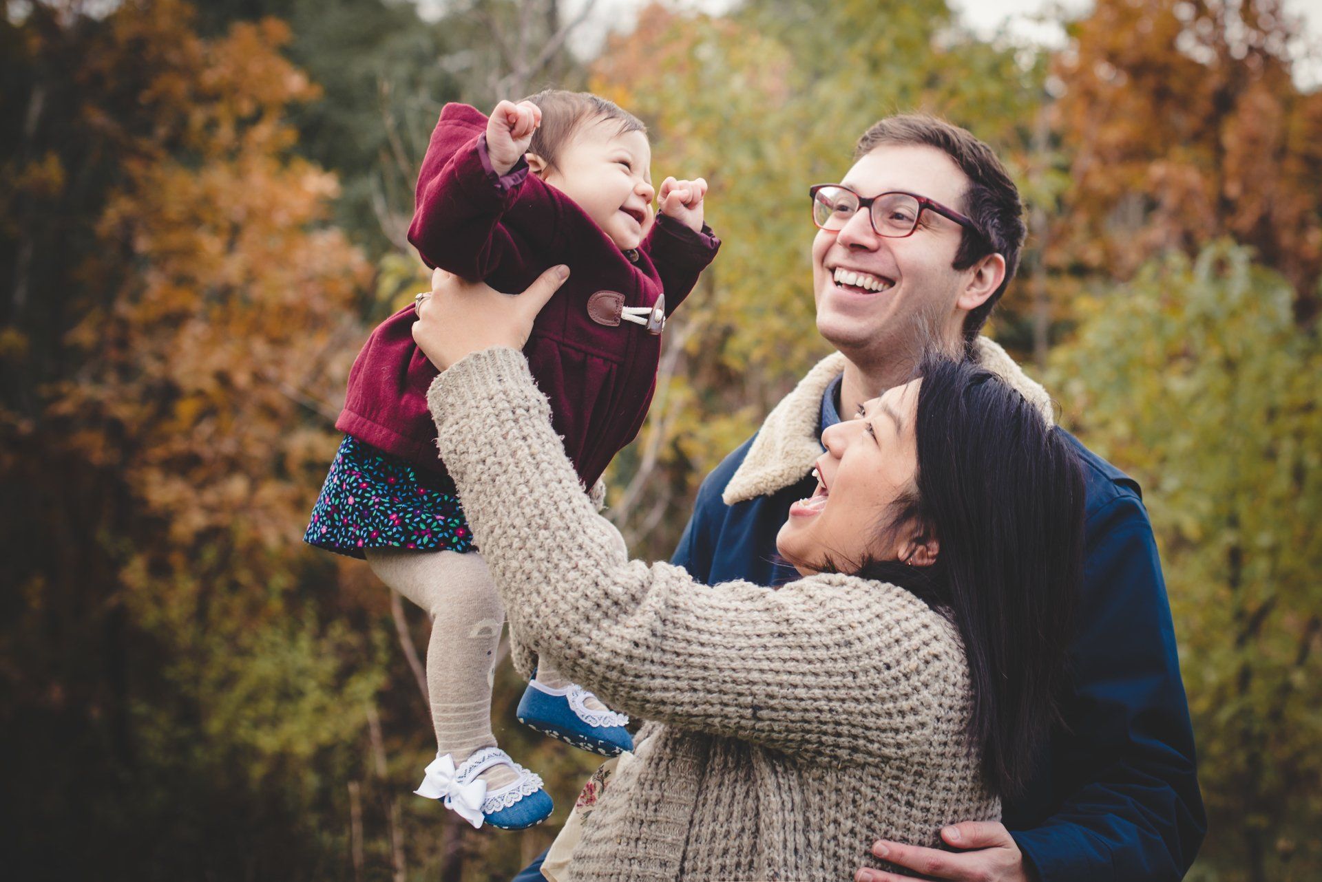 Photo of mom holding up her smiling toddler while dad looks on for toronto gift card idea