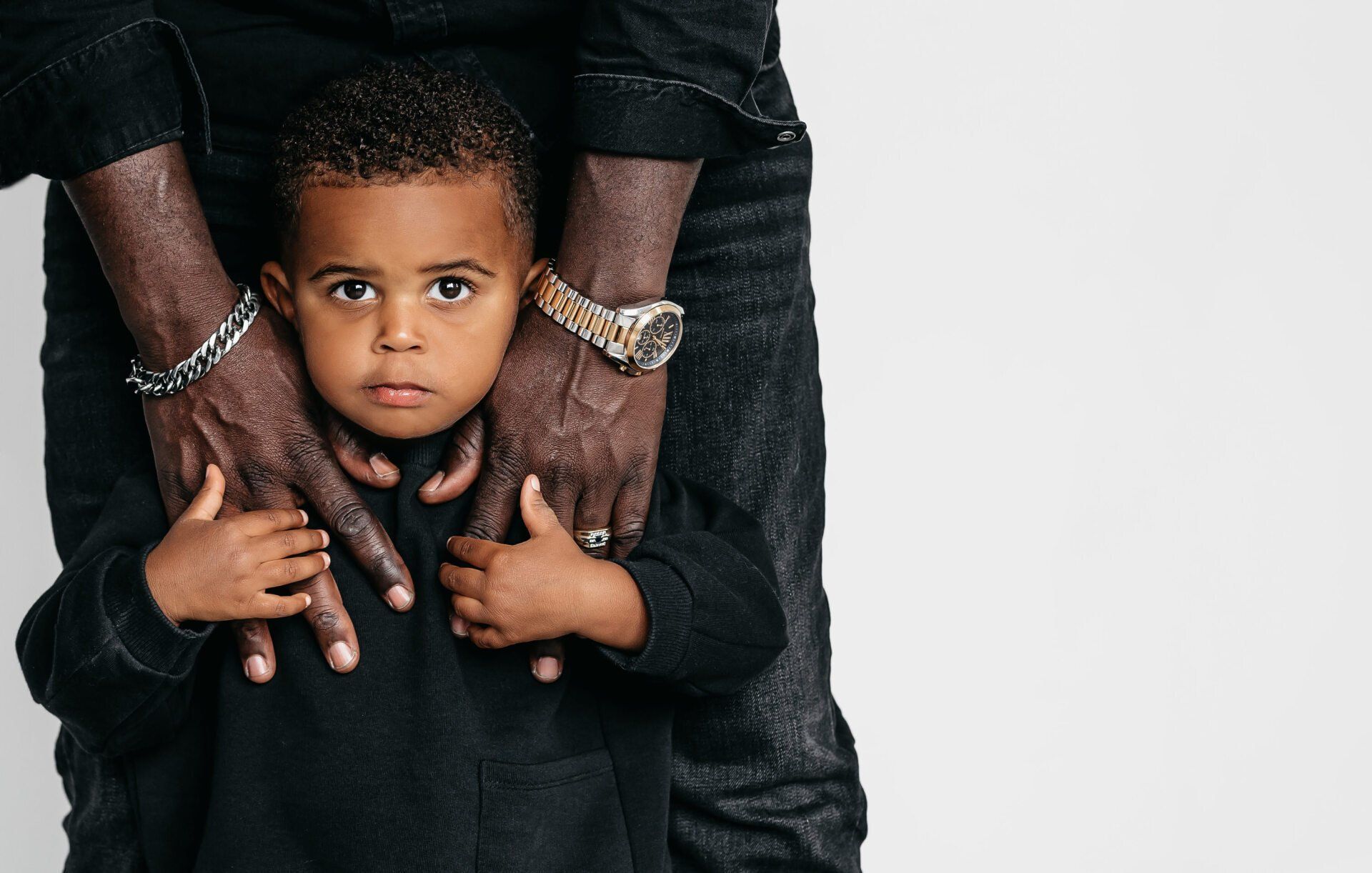 Toddler standing between dad’s legs for family photography