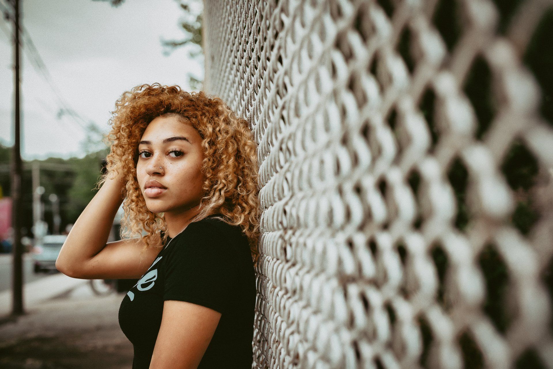 Young woman standing against chain link fence for personal branding gift card
