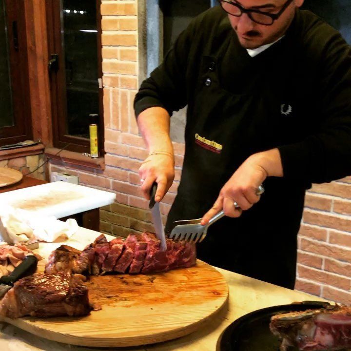Cuoco di un ristorante mentre serve una bistecca di carne