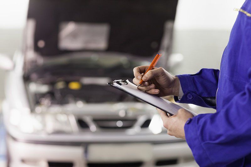 Mechanic Writing On A Clipboard In A Garage— Illawarra Car Service Centre In Oak Flats NSW