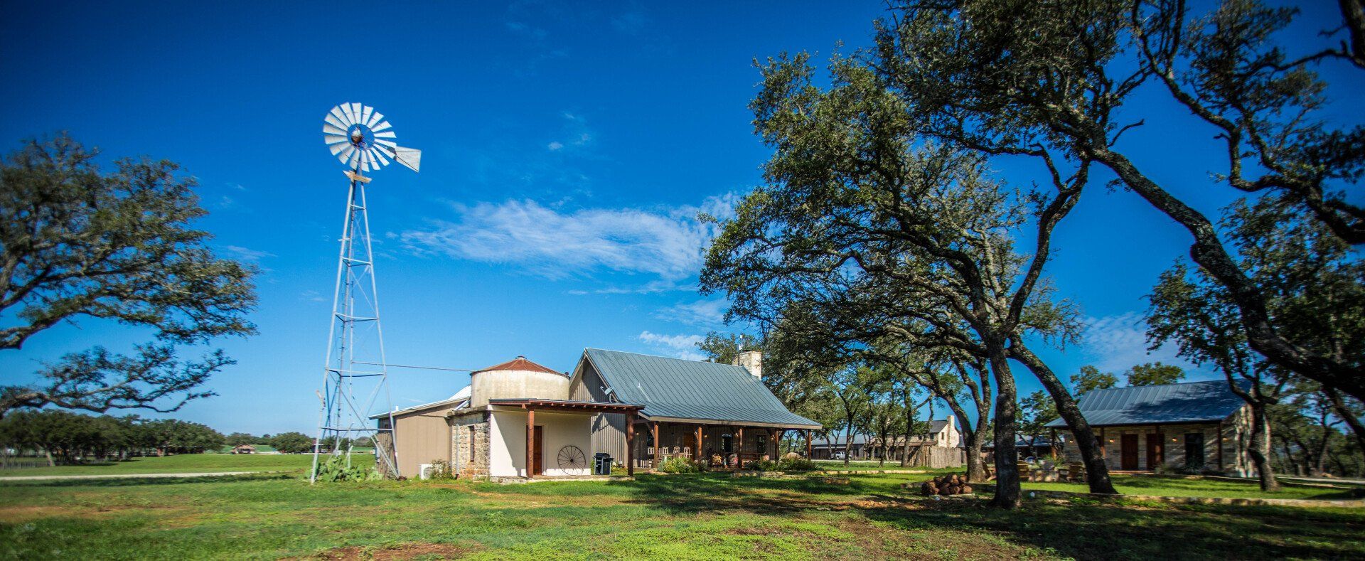 Windmill and rustic building under a bright blue sky.