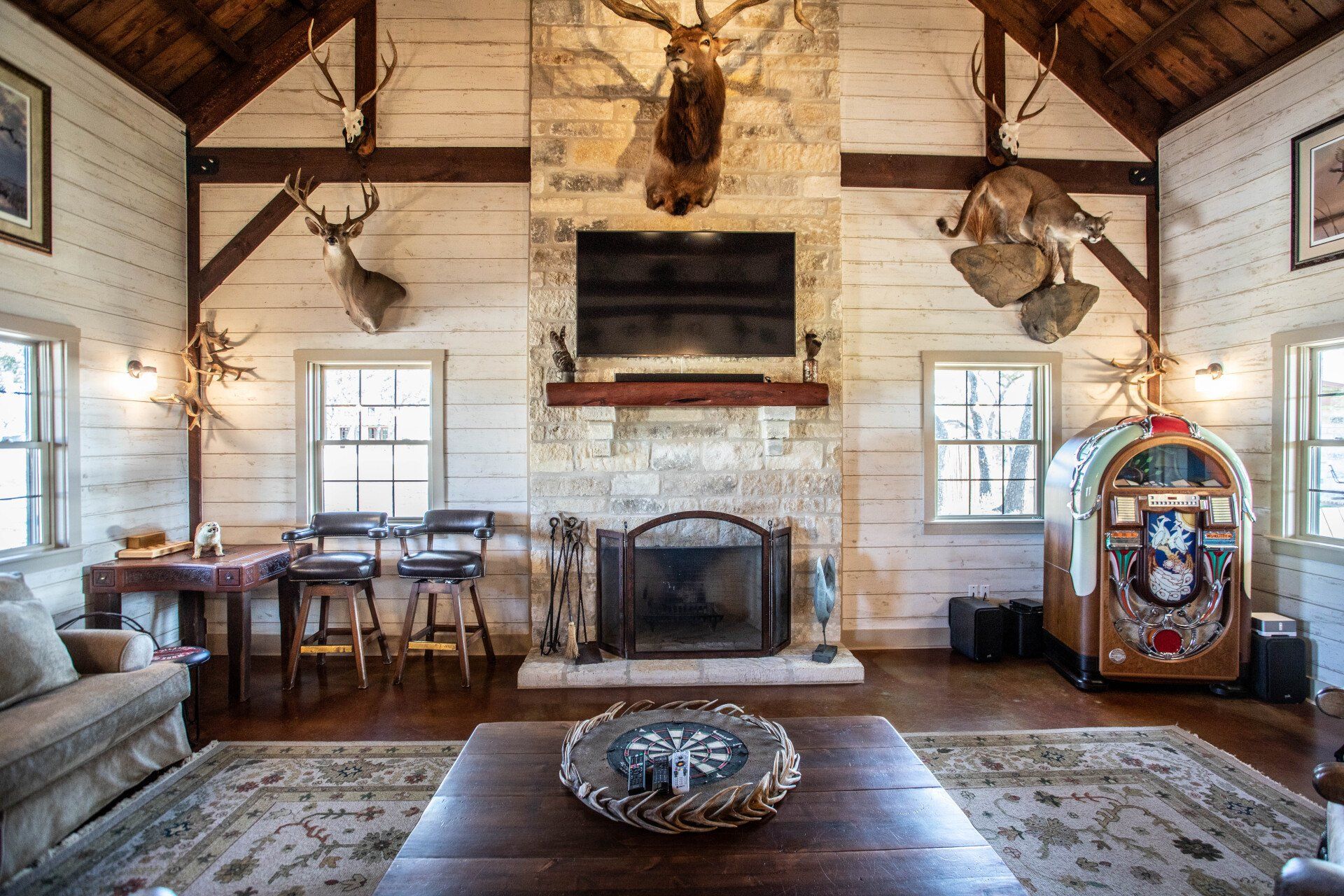 Rustic living room with taxidermy, fireplace, and jukebox.
