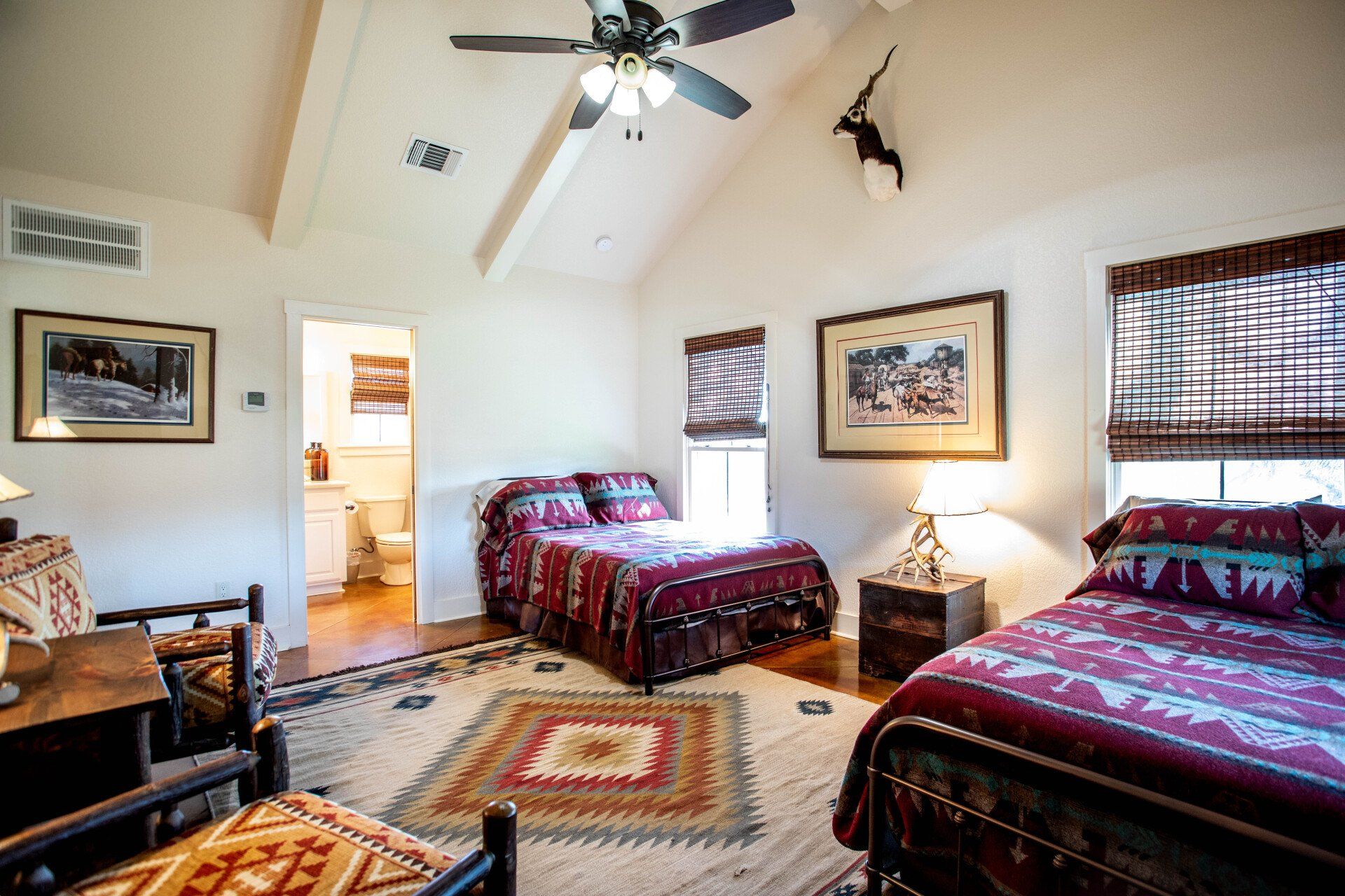 Bedroom with two beds, Southwestern rug, and decor; includes a view of the bathroom.