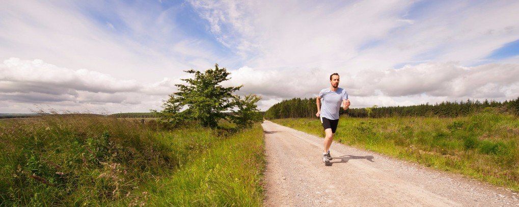 A man is running down a dirt road in a field.