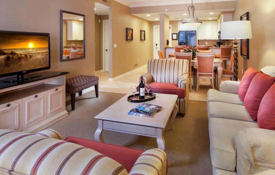 Cozy living room with striped sofa, coffee table, TV, and dining area in the background