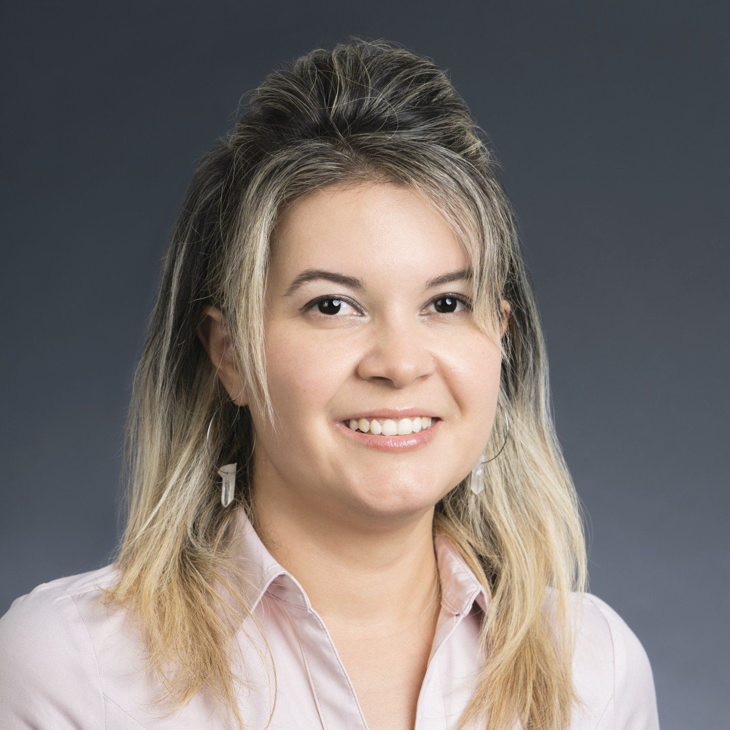 Smiling woman in a light pink blouse against a dark gray background