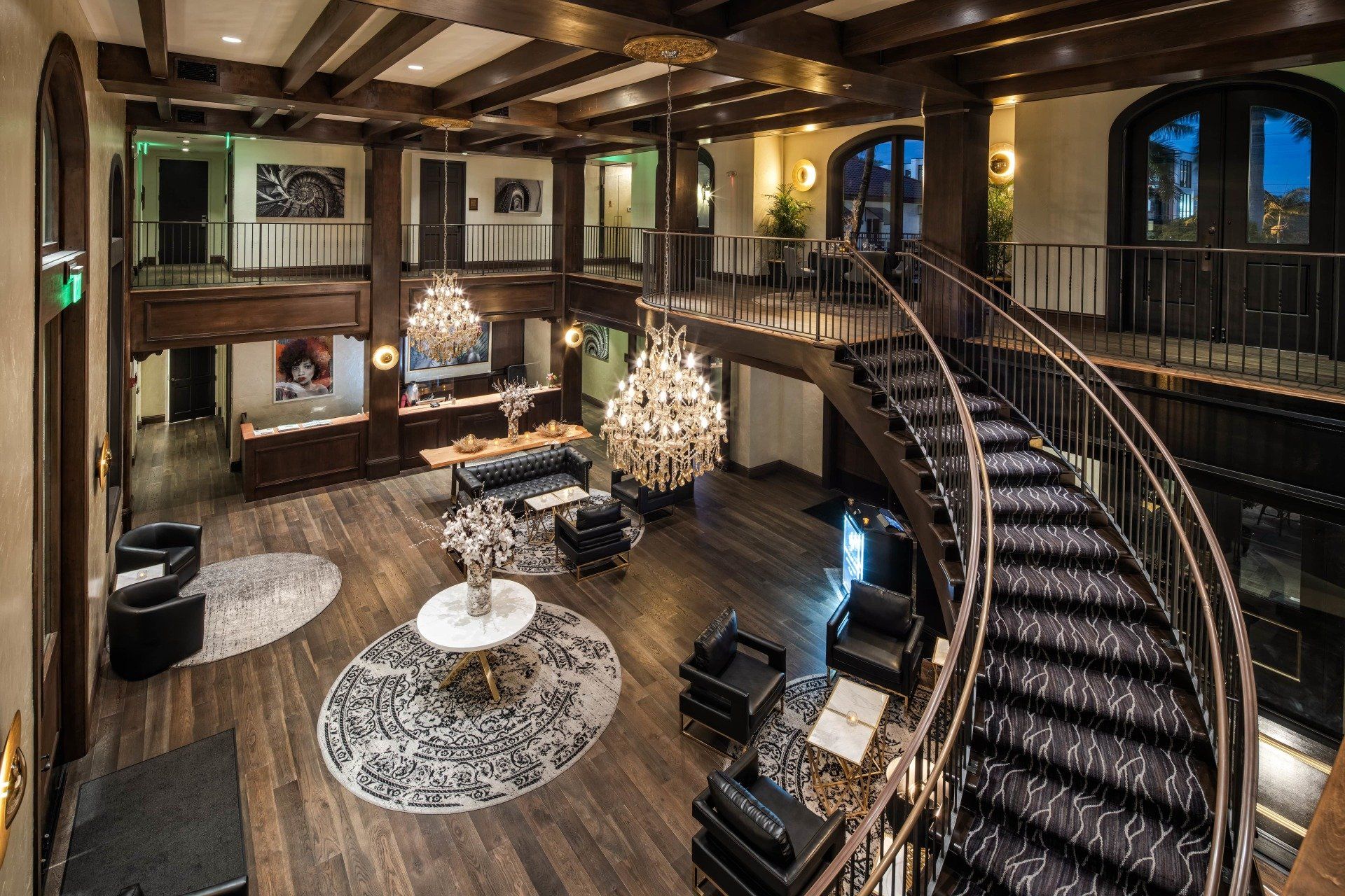 Luxurious rustic living room with a grand curved staircase, fireplace, and chandelier
