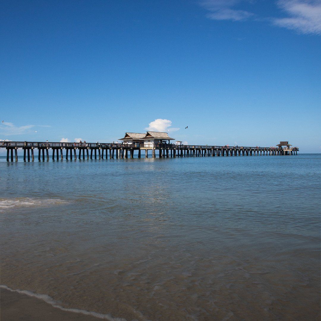 Long wooden pier over calm blue water under a clear sky