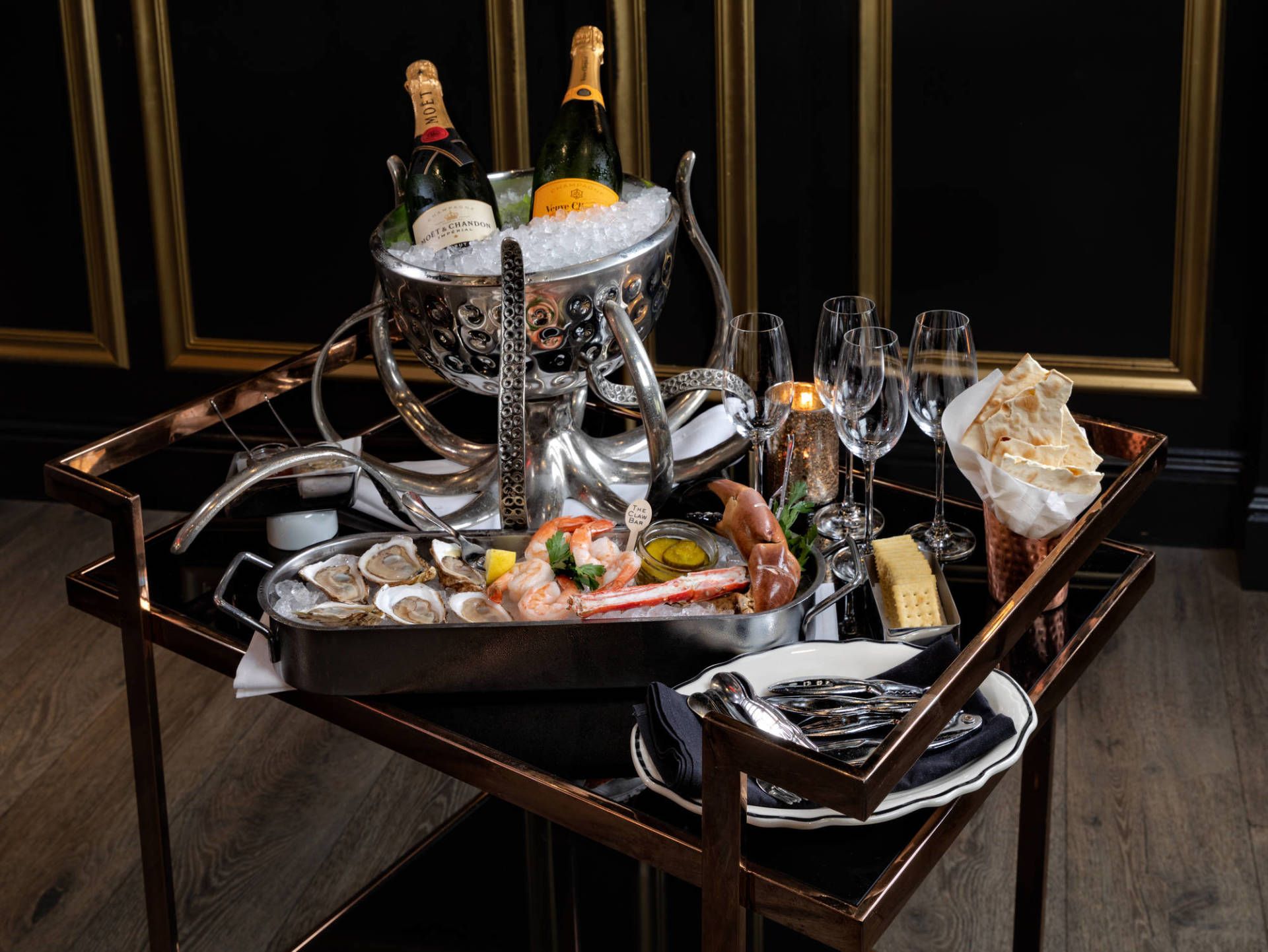 Luxurious seafood and champagne display on a black tray table in a dark, elegant setting