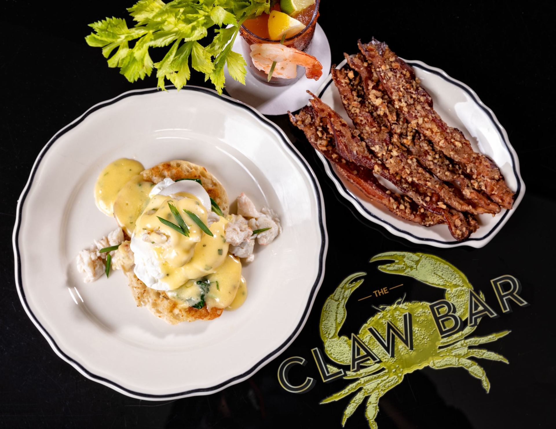 Plated eggs benedict and grilled meat on white dishes, with garnish and CLAW BAR branding on black background