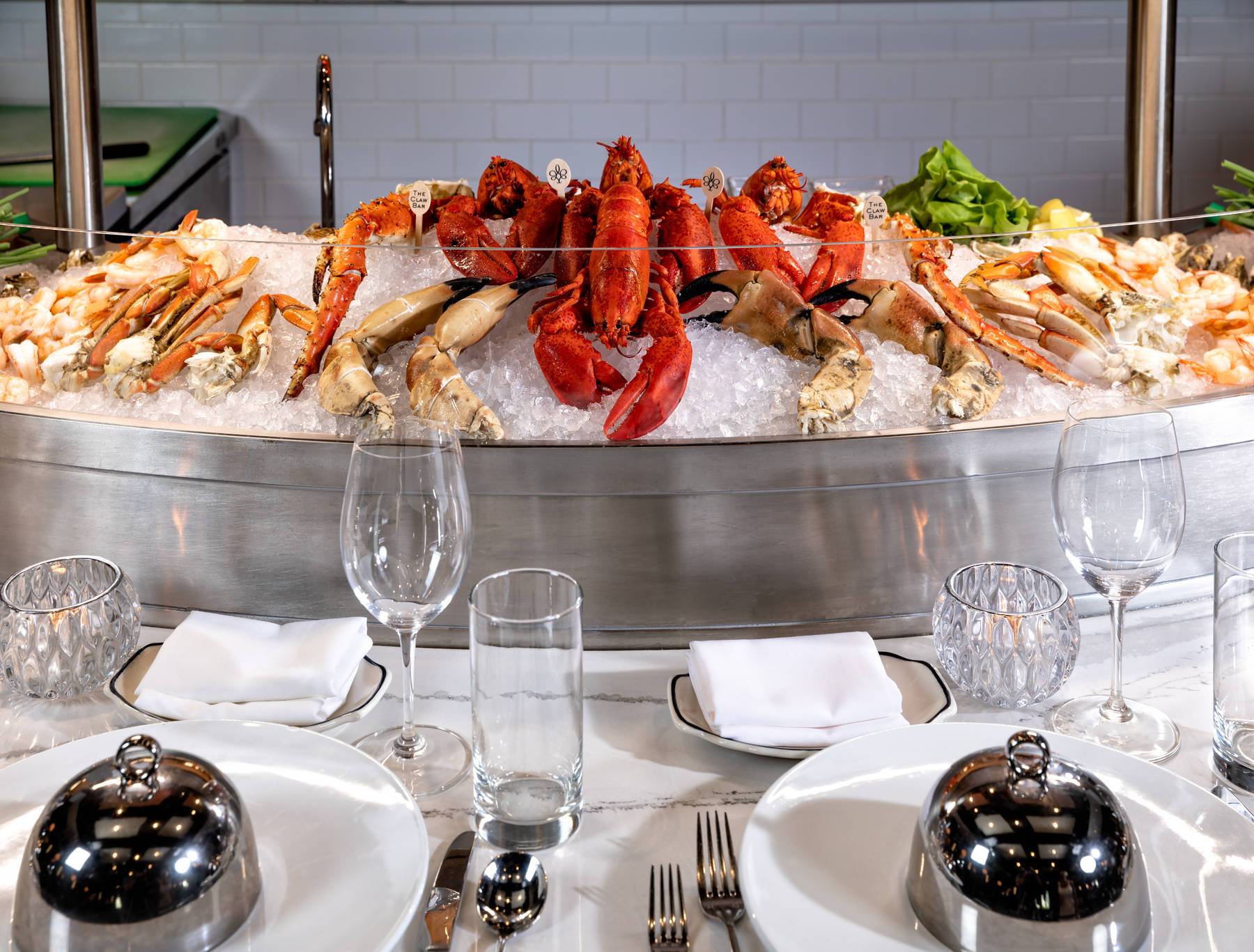 Elegant seafood buffet with crab legs and lobster on ice, set on a white dining table.