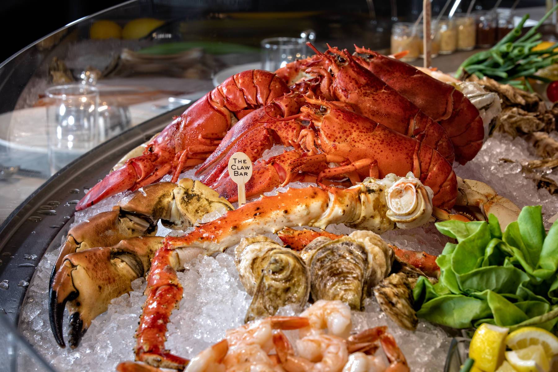 Seafood platter with lobster, shrimp, oysters, and lemon wedges on ice