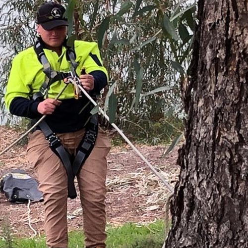 man in safety jacket tied to a tree