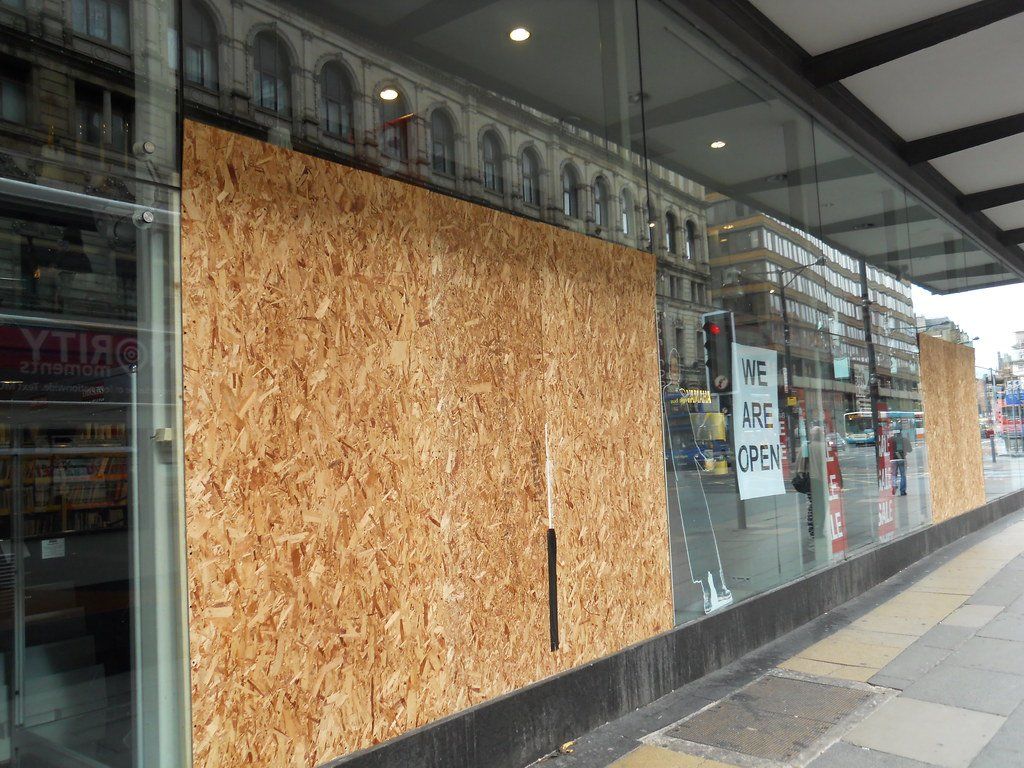 A building with a lot of windows covered in plywood.
