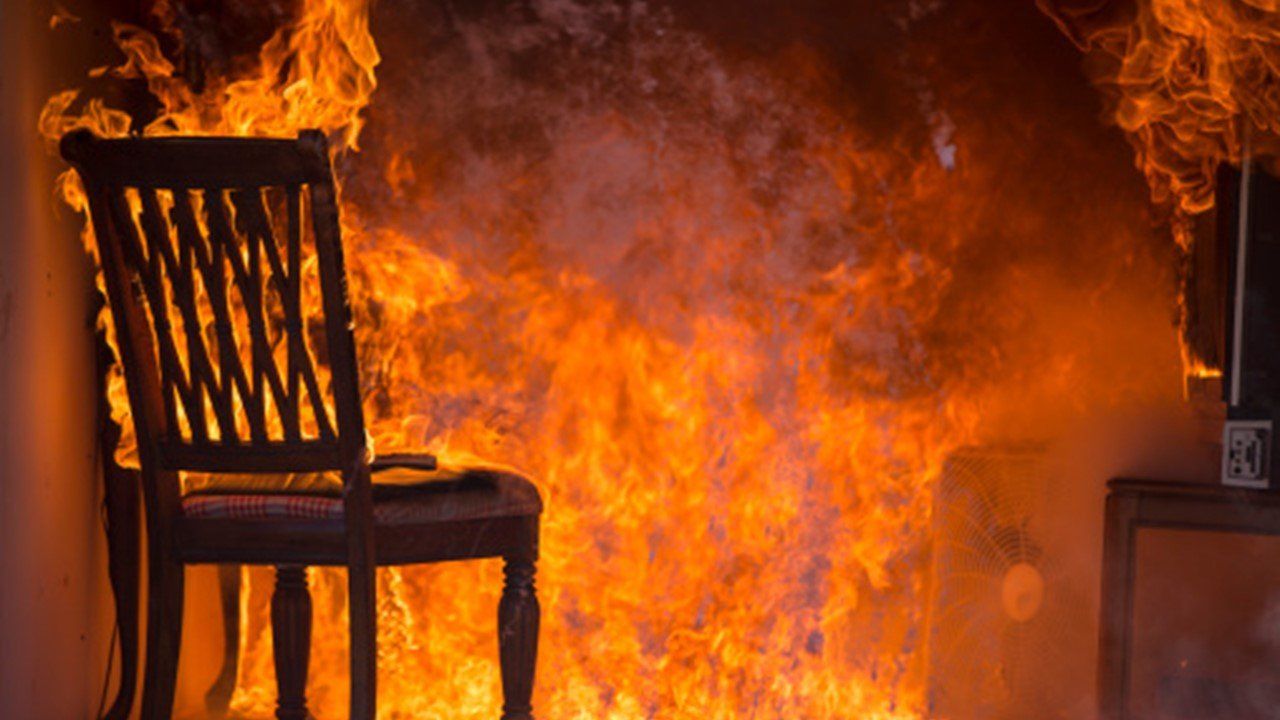 A chair is sitting in front of a wall of flames.