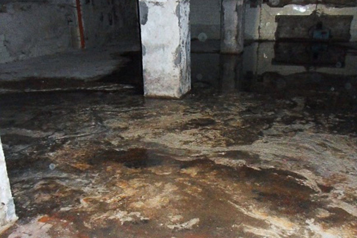 A dirty basement with a pillar in the middle of it.
