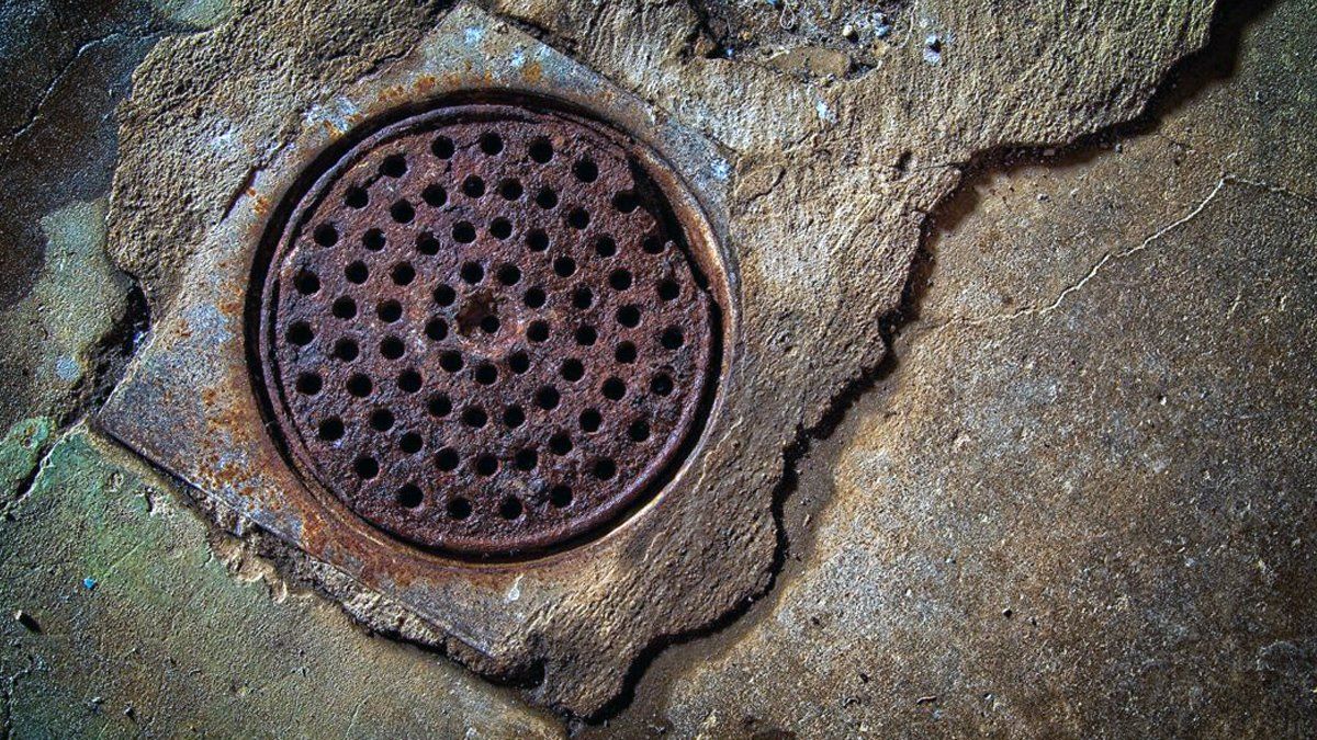 A rusty manhole cover is sitting on the ground.