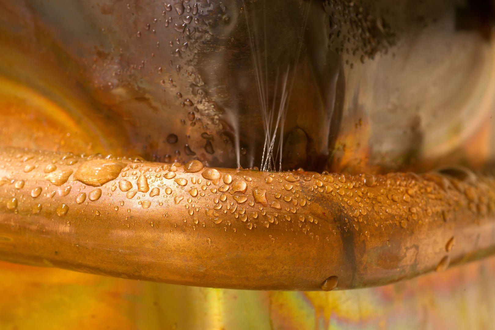 A close up of a copper pipe with water drops on it.