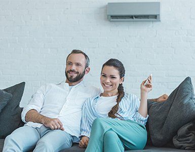 Indoor Air Quality — Couple Turning On The Air Conditioner in Port Lavaca, TX Indoor Air Quality — Couple Turning On The Air Conditioner in Port Lavaca, TX