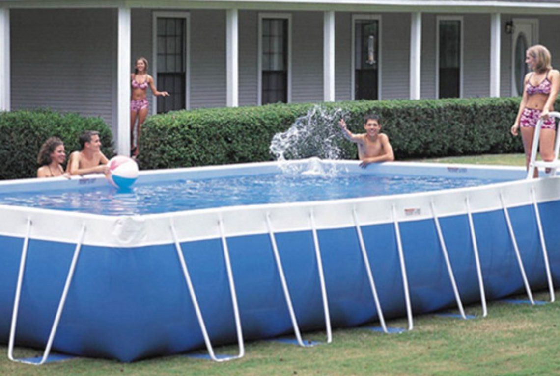 People splashing in a blue above-ground pool in a yard