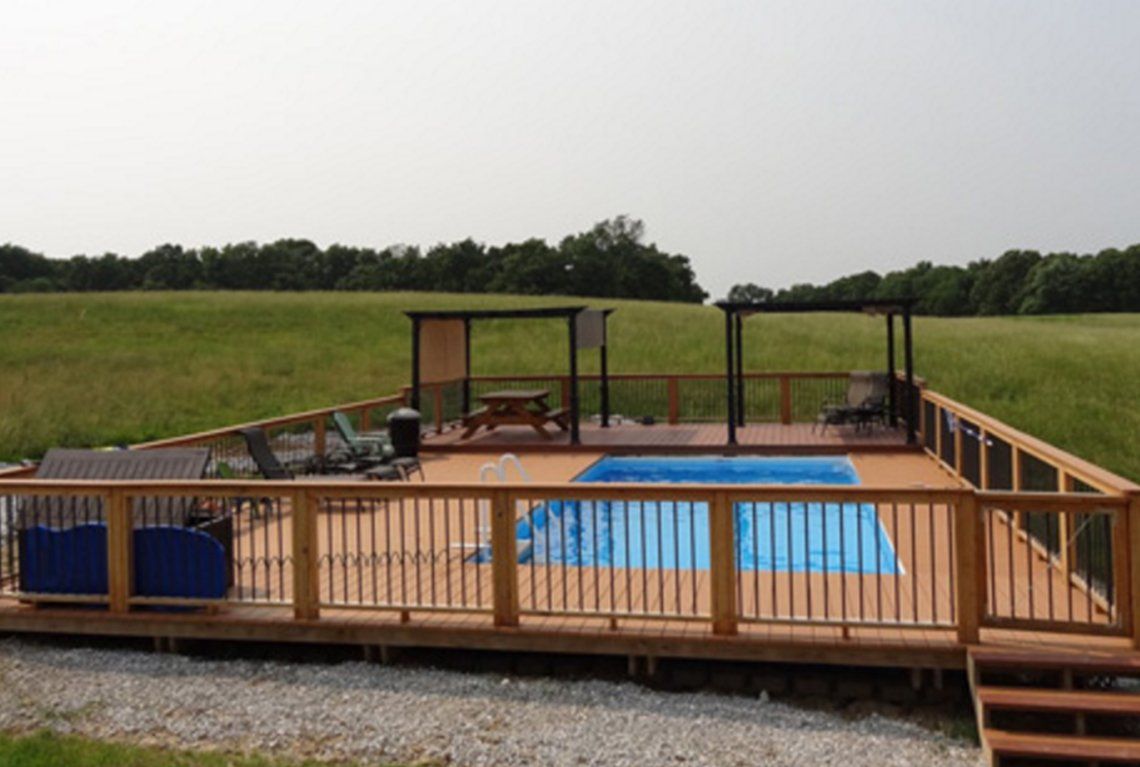 Wooden deck with above-ground pool, lounge chairs, and gazebo overlooking a grassy field