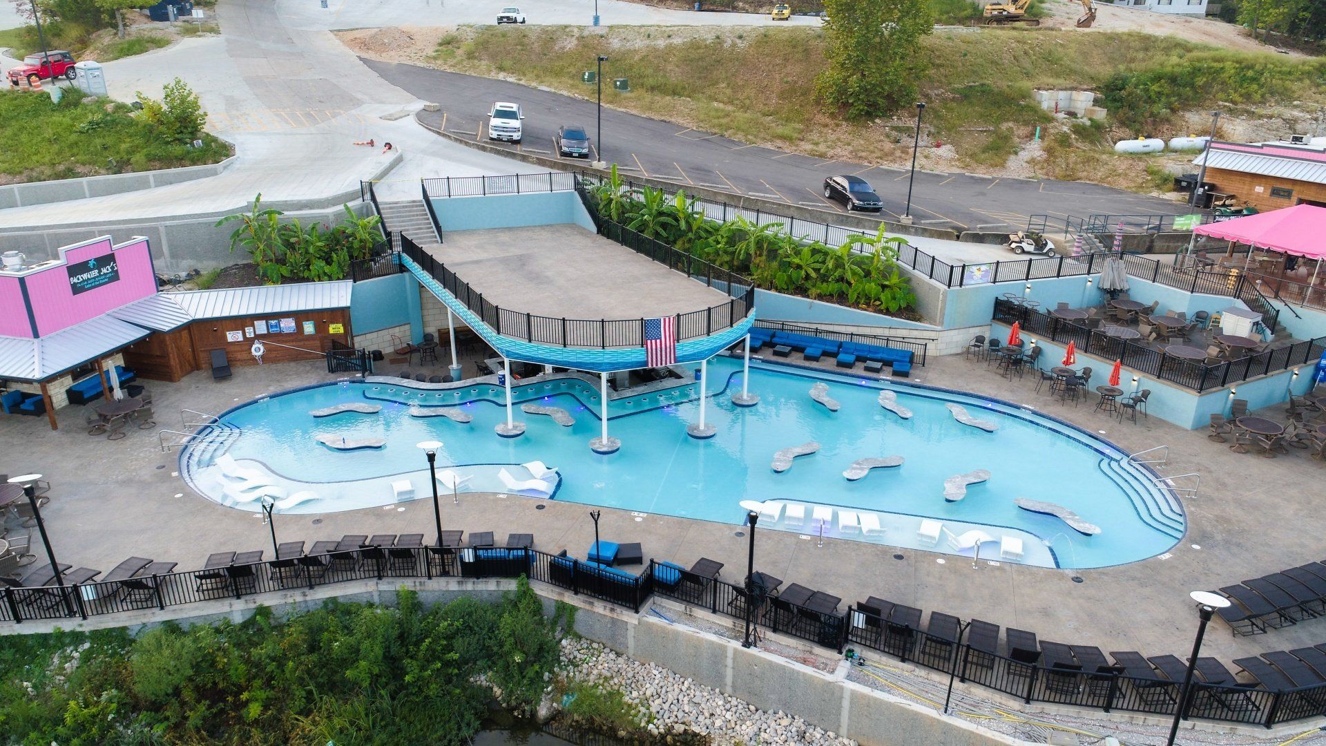 Outdoor swimming pool with a shallow splash area, blue water, umbrellas, and surrounding lounge chairs