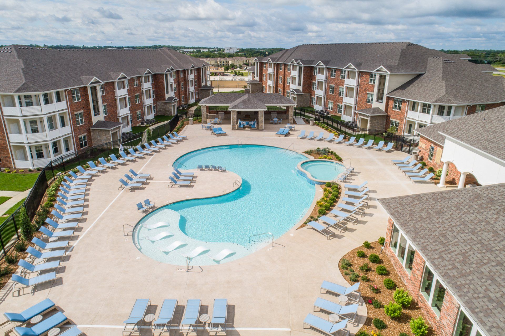Aerial view of a resort courtyard with a large swimming pool and lounge chairs surrounding it