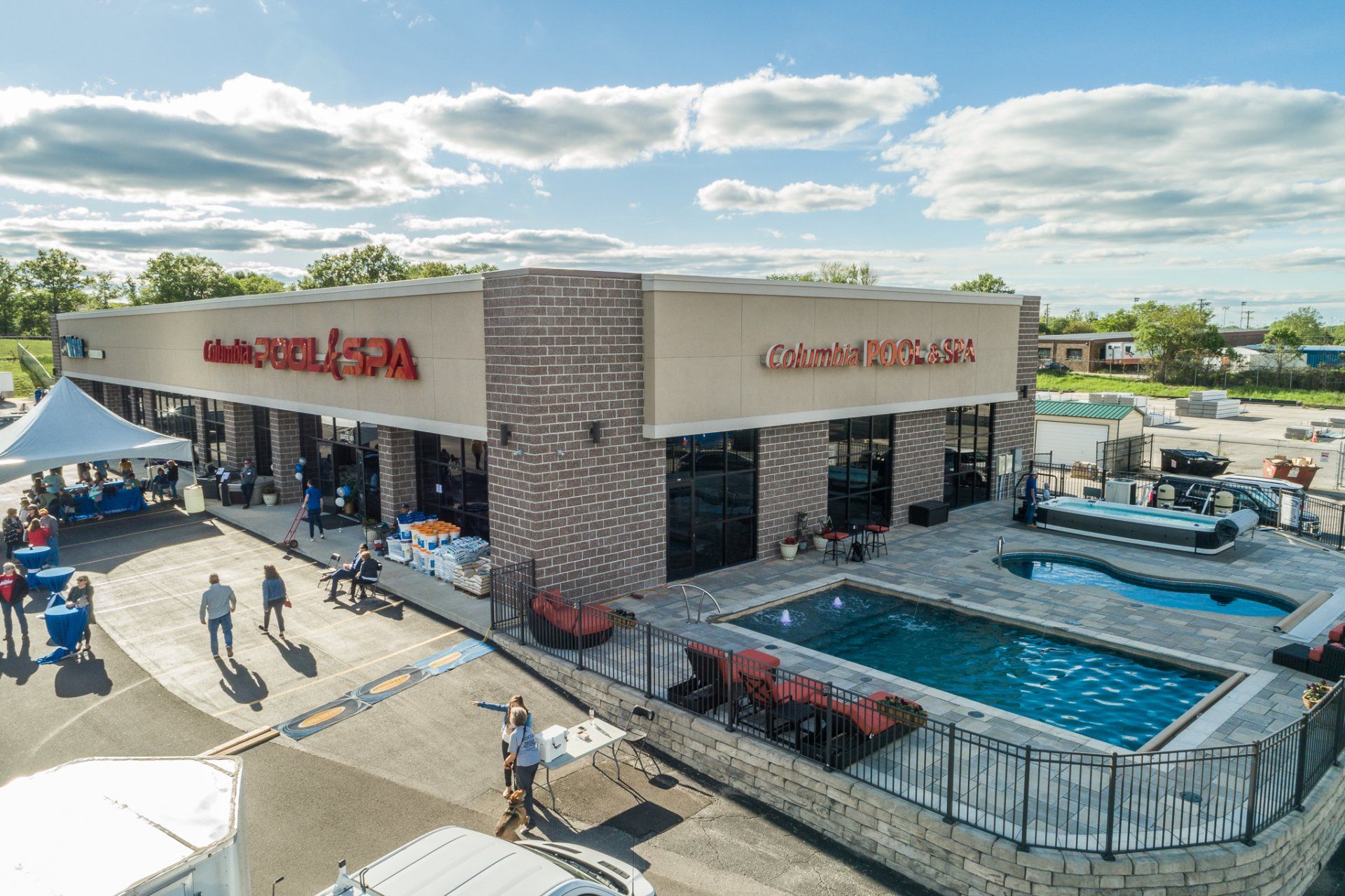 Outdoor shopping center with a poolside patio, blue umbrellas, and a Red Robin restaurant under a bright sky