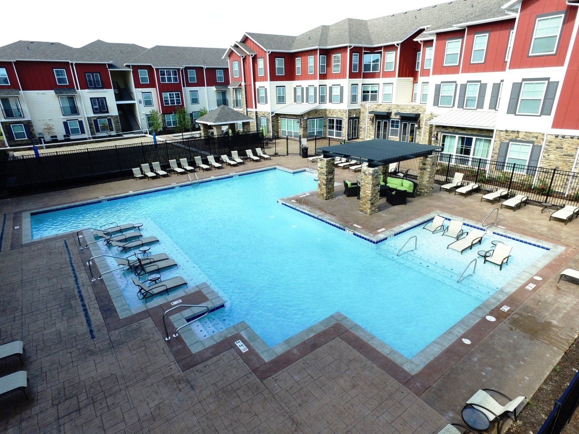 Courtyard pool with blue water, lounge chairs, and surrounding red-and-white apartment buildings