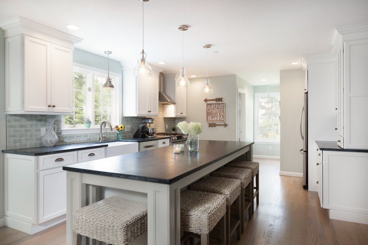 Bright modern white kitchen with dark island, pendant lights, and a window by the sink
