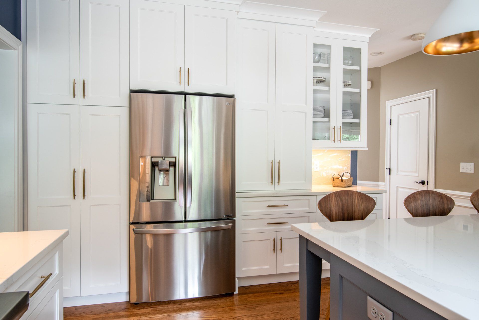 Modern white kitchen with stainless steel refrigerator and island countertop, decorated with bowls.