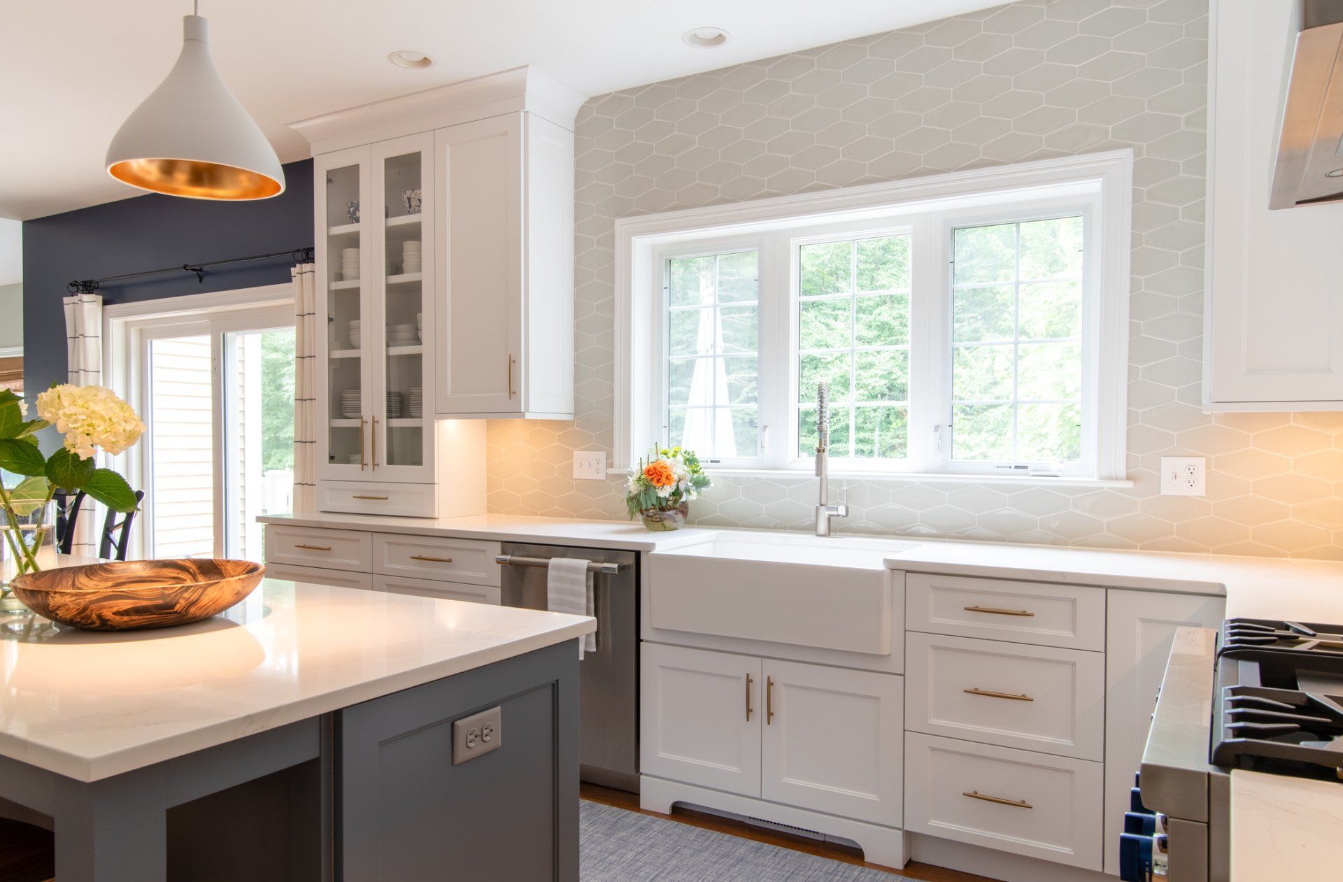 Bright modern kitchen with white cabinets, gray island, and large window above the sink