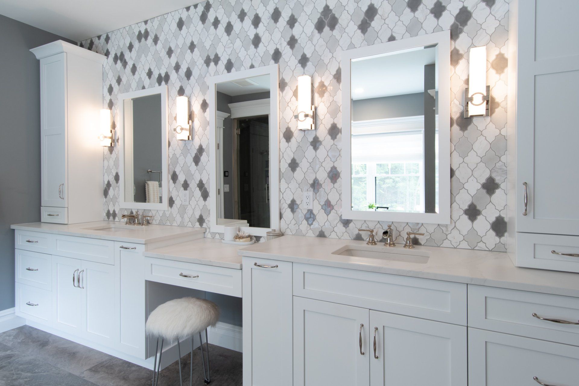Bright white bathroom vanity with double mirrors, wall sconces, and gray diamond-pattern wallpaper