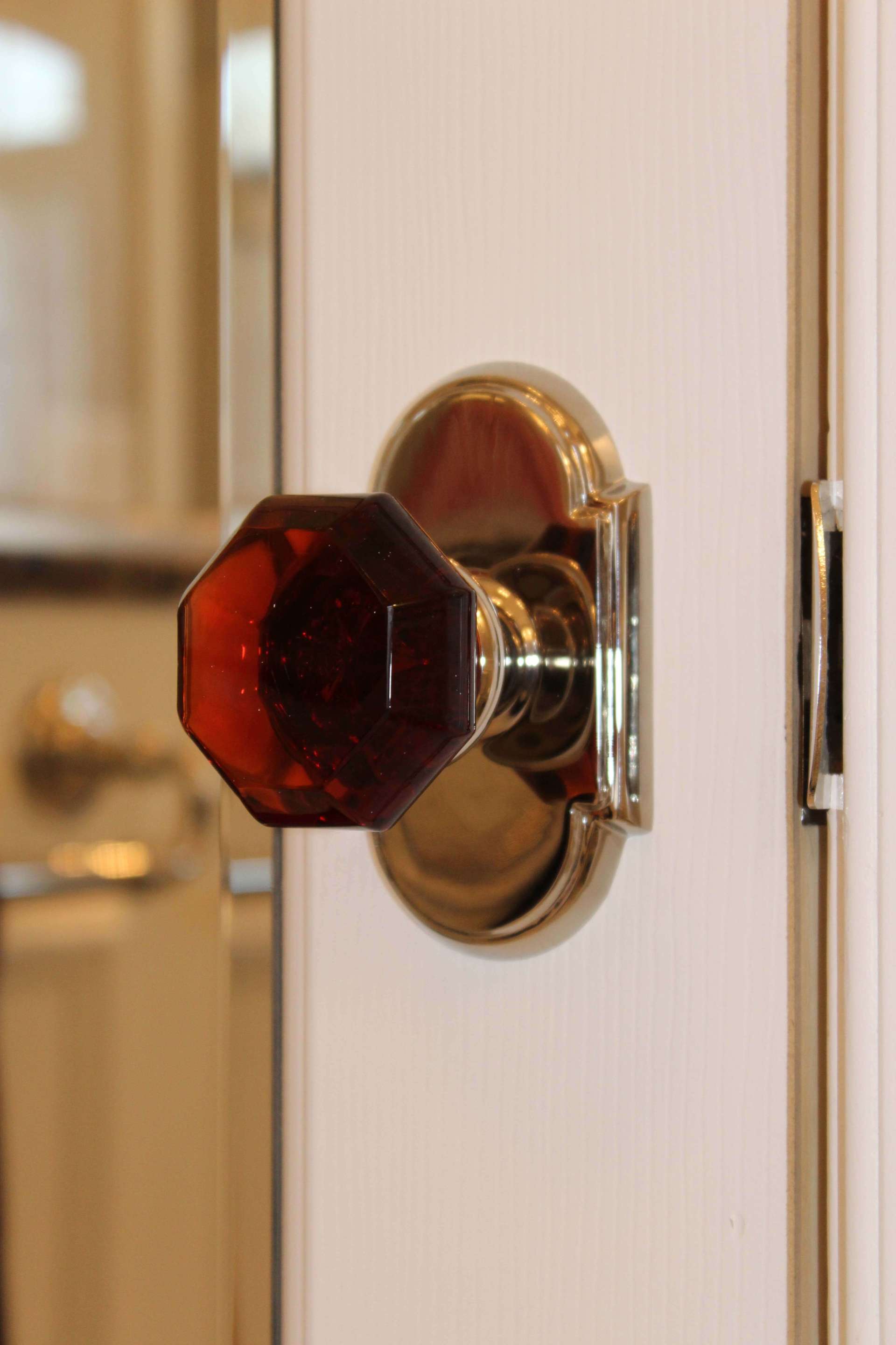Dark red crystal doorknob on a white door with a brass backplate