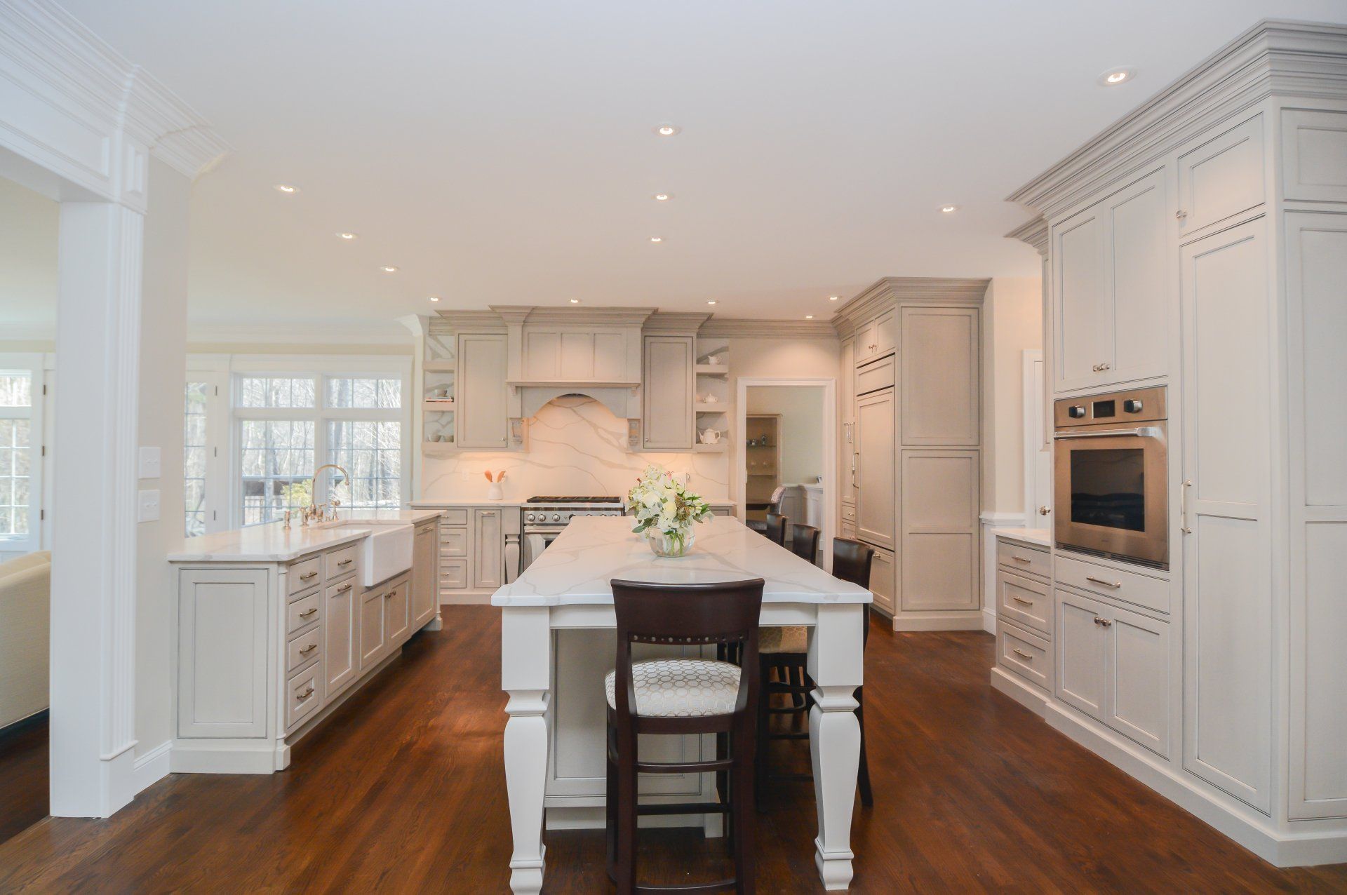 Bright white modern kitchen with island, dark wood floors, and built-in cabinetry