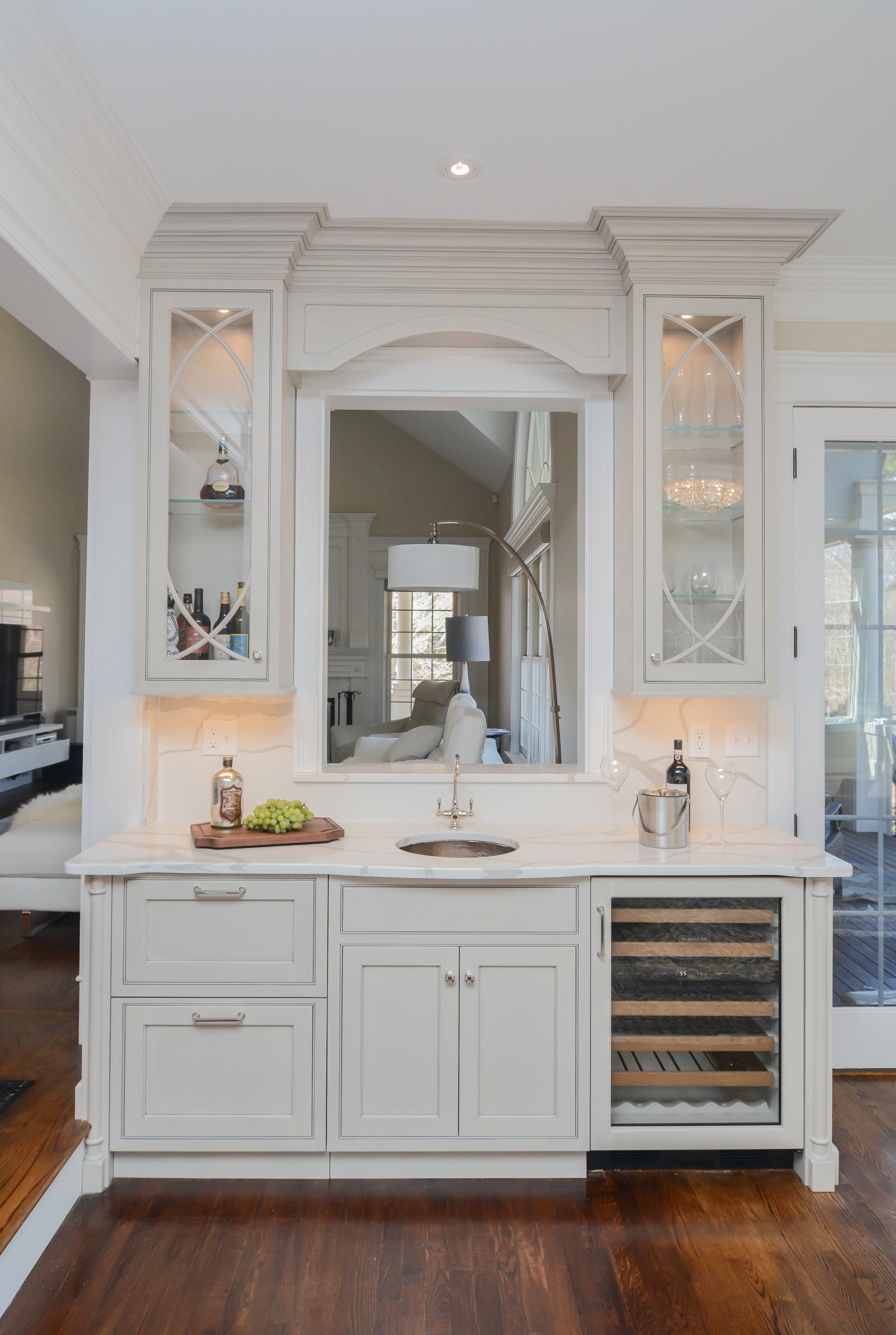 White bathroom vanity with ornate mirror, glass cabinets, sink, and wine cooler on dark wood floor