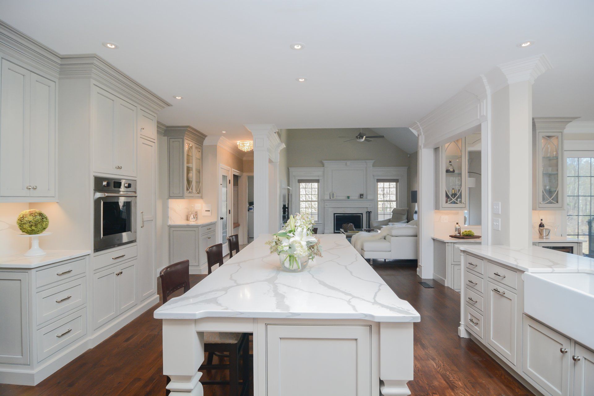 Bright white modern kitchen with large island, dark wood floors, and built-in appliances