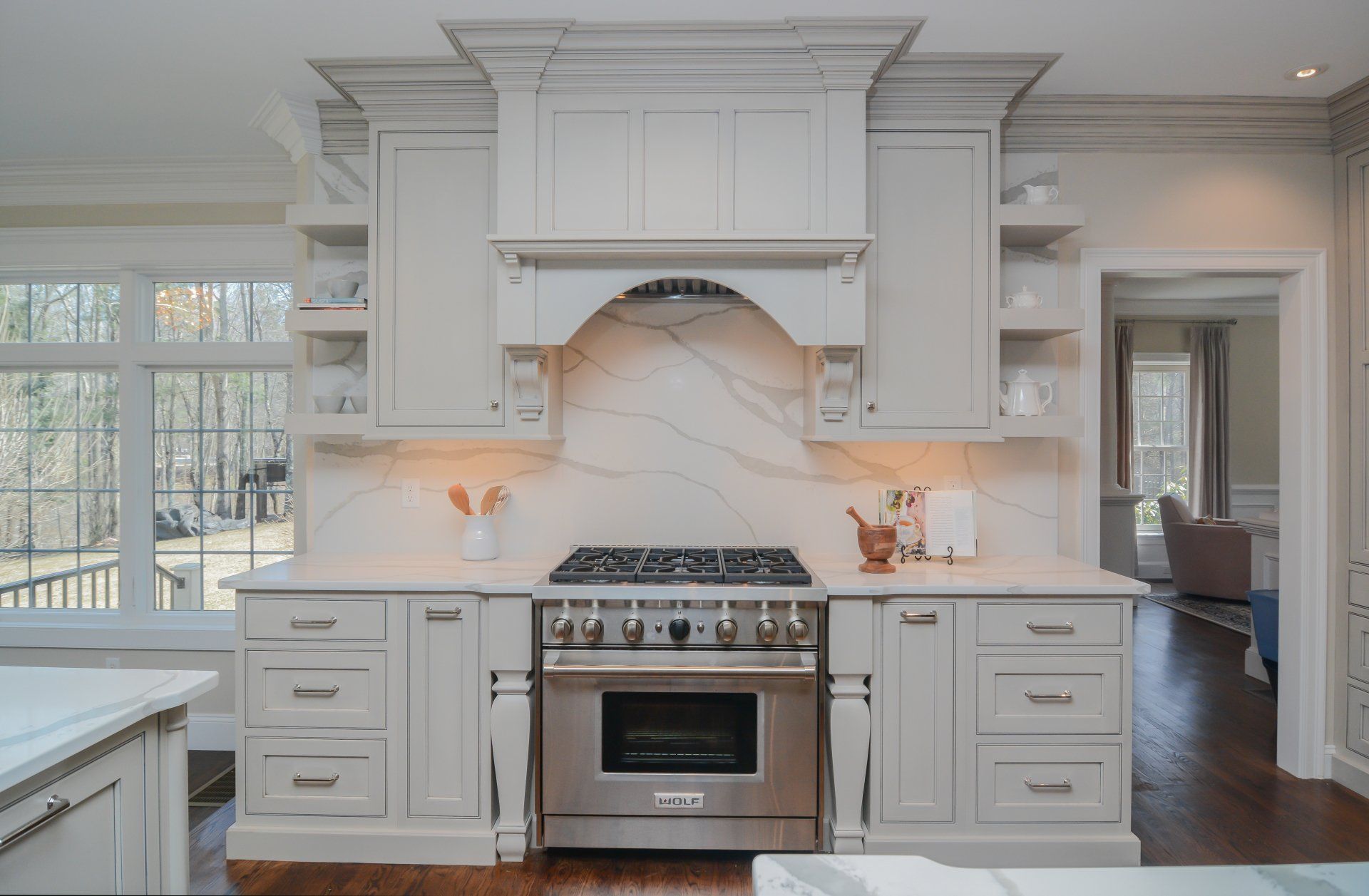 Bright white kitchen with ornate range hood, gas stove, and light hardwood floors