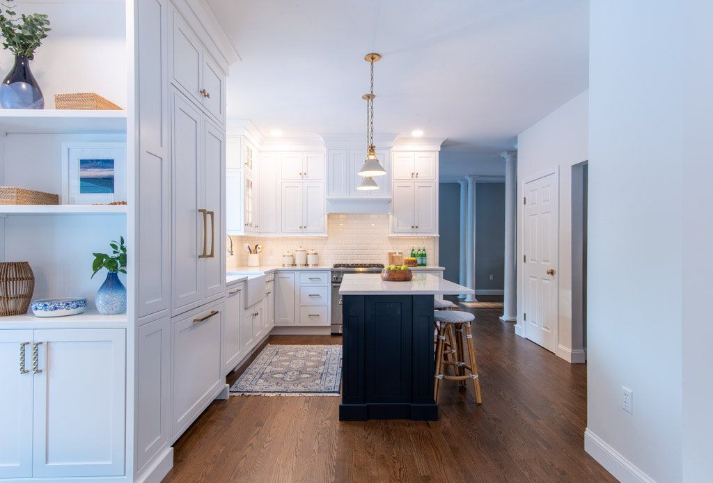 Bright white kitchen with dark wood floor, central island, pendant light, and built-in cabinets