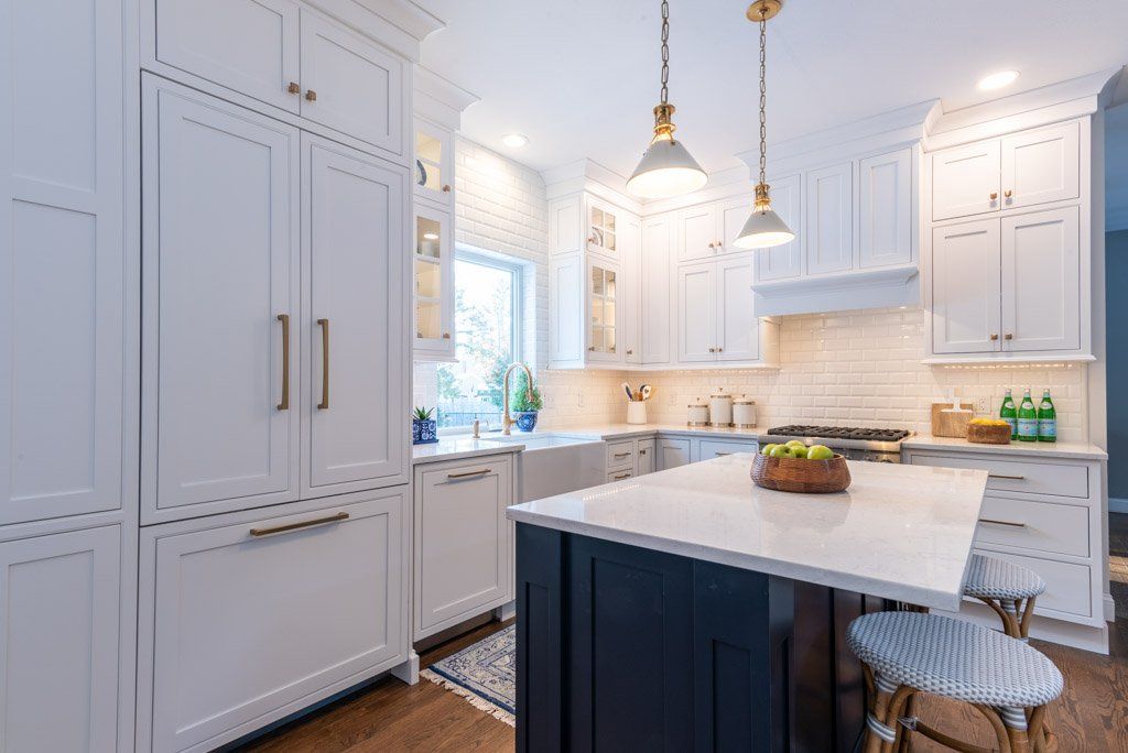 Bright white kitchen with marble island, pendant lights, and built-in cabinetry