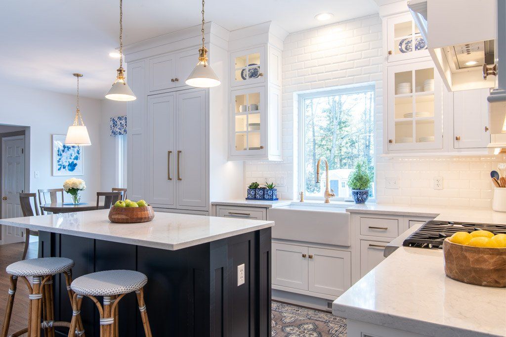 Bright modern white kitchen with marble island, pendant lights, and large window over the sink
