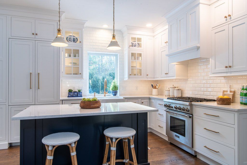 Bright white kitchen with island, stools, pendant lights, and a window over the sink